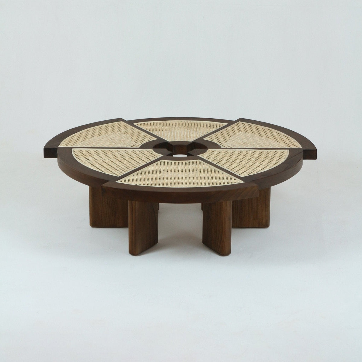 Low round natural oak coffee table with segmented woven cane top, circular center opening and chunky solid-wood base supported by short vertical legs, modern mid-century minimalist design.