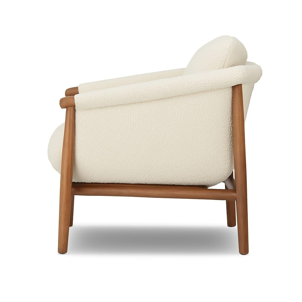 Side profile of a cream boucle-upholstered accent chair with rounded arms and cushioned back, supported by a natural wood frame and tapered legs in a modern mid-century style.