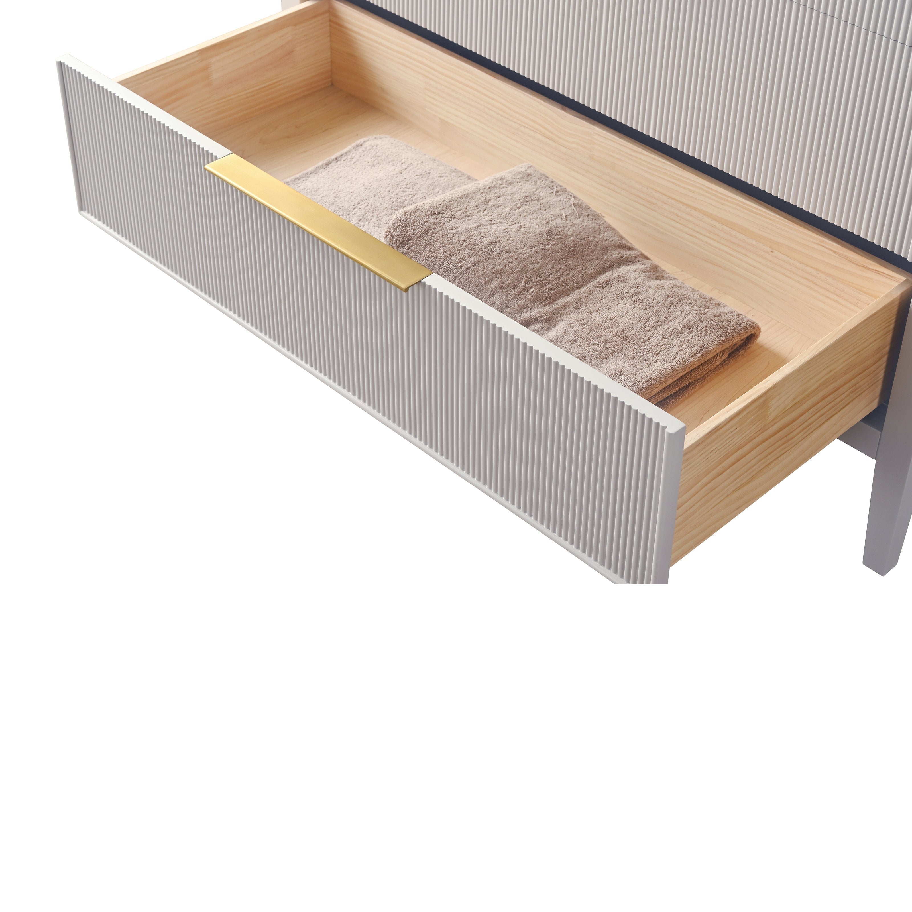 Close-up of an open modern bathroom vanity drawer with a ribbed stone-colored front, solid wood interior, folded taupe towel and a slim brushed gold handle.