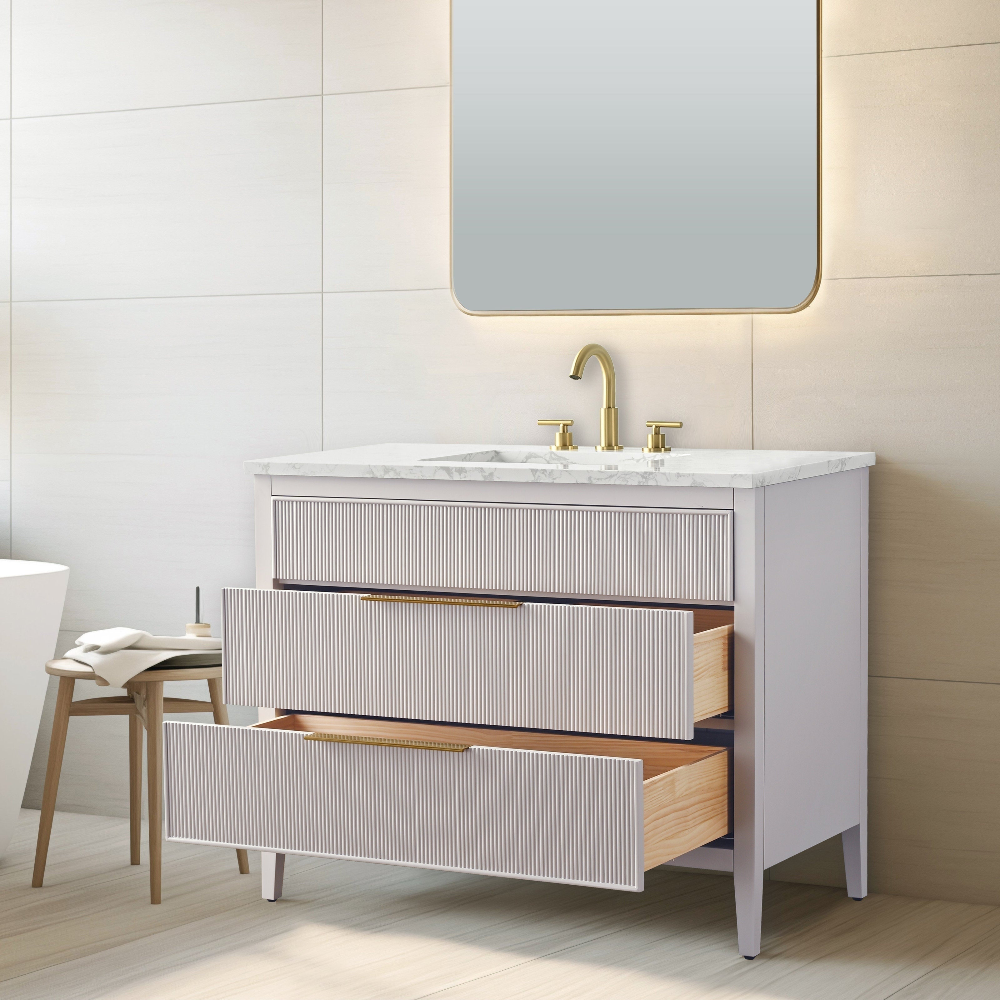 Freestanding modern single-sink bathroom vanity in light wood with a white stone countertop, ribbed drawer fronts and brass faucet and handles; two drawers pulled open to show natural wood interiors beneath a backlit mirror.