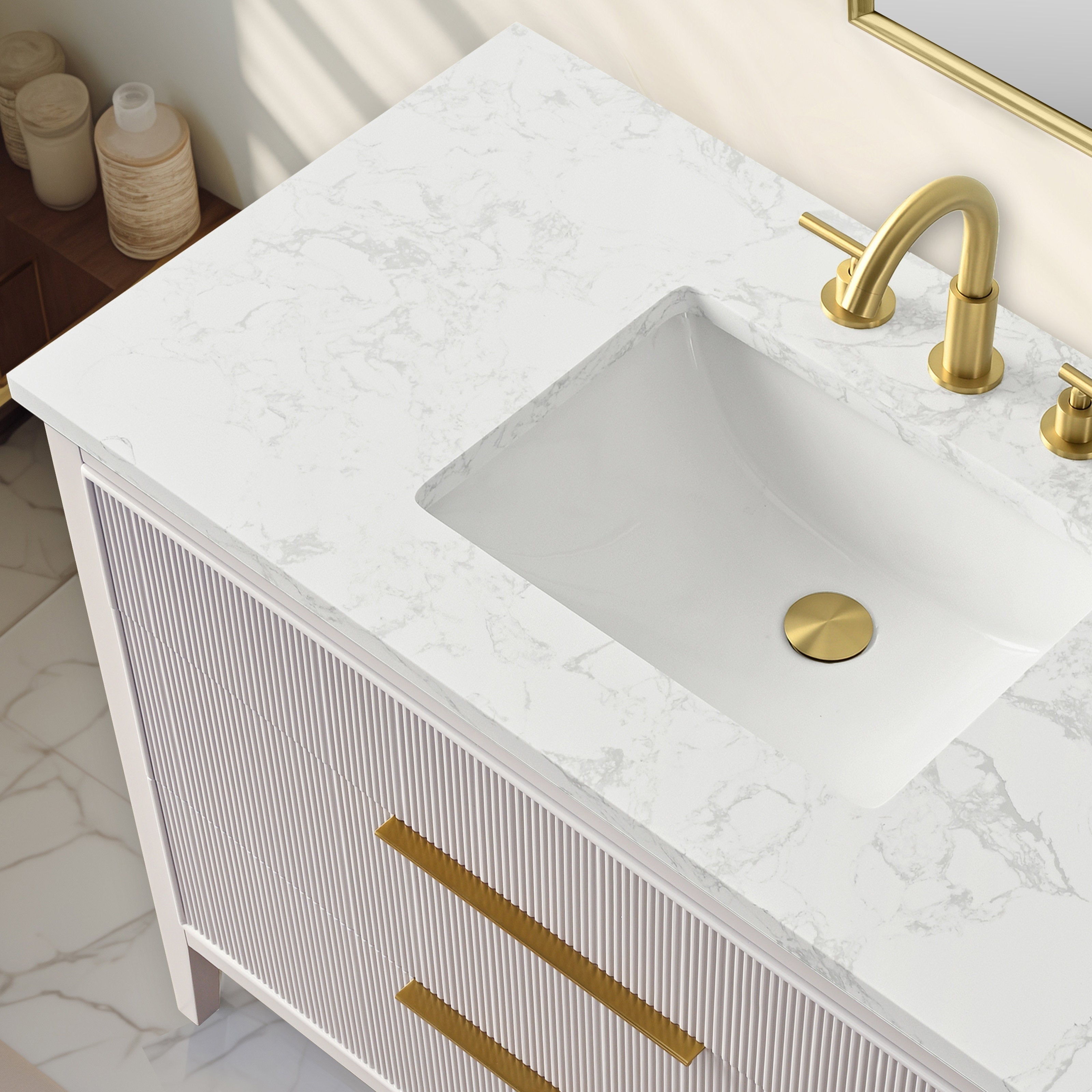 Top-down view of a modern freestanding solid-wood bathroom vanity with a white stone countertop with gray veining, rectangular undermount ceramic sink, brushed gold faucet and drain, and fluted wood drawer fronts with gold handles.