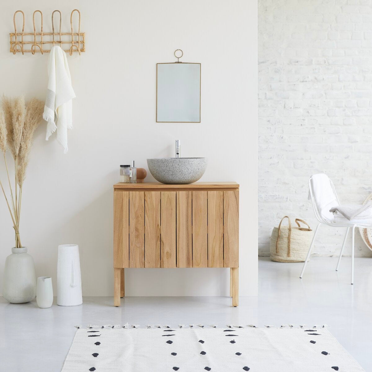 31-inch modern solid wood bathroom vanity in natural teak with a grey terrazzo round vessel sink and chrome faucet, shown in a minimalist bathroom with a small hanging mirror, pampas grass, woven basket and white chair.