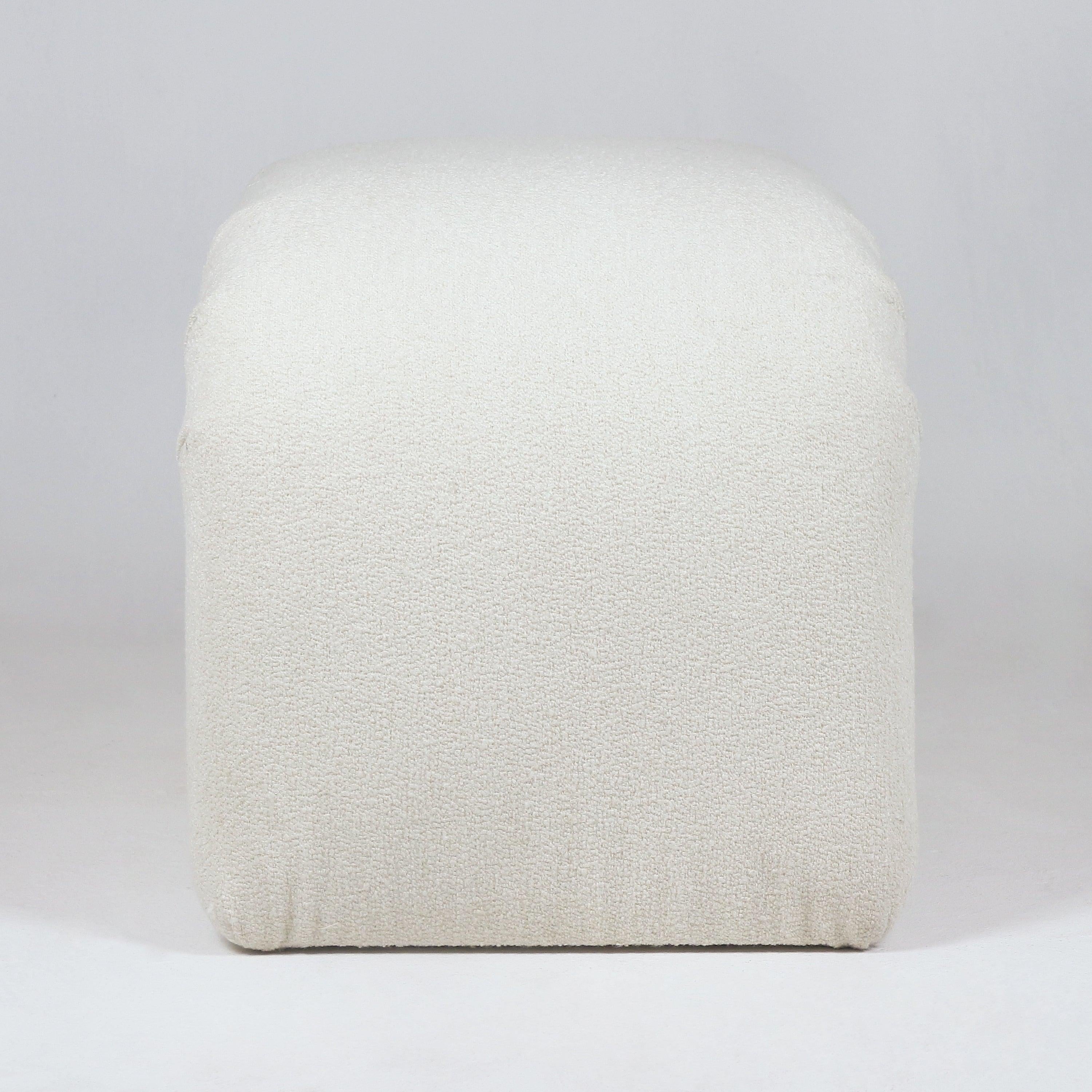 Front-facing view of a cream boucle upholstered backless vanity stool with soft rounded corners and textured fabric, shown without visible legs in a minimalist coastal-contemporary style.