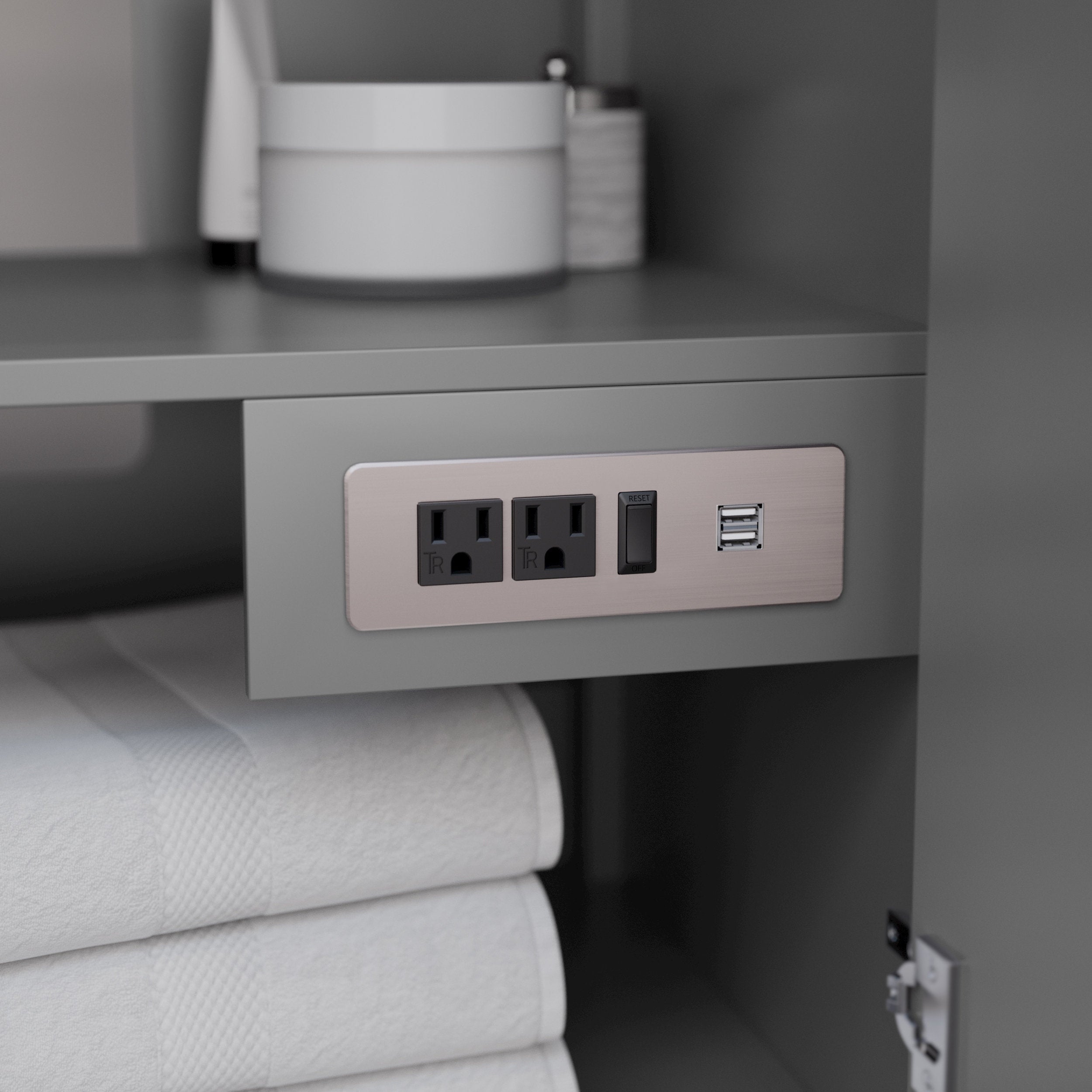 Interior of a stone-colored solid wood vanity cabinet showing a brushed-metal outlet plate with two power sockets, a reset switch and dual USB ports above neatly folded white towels.