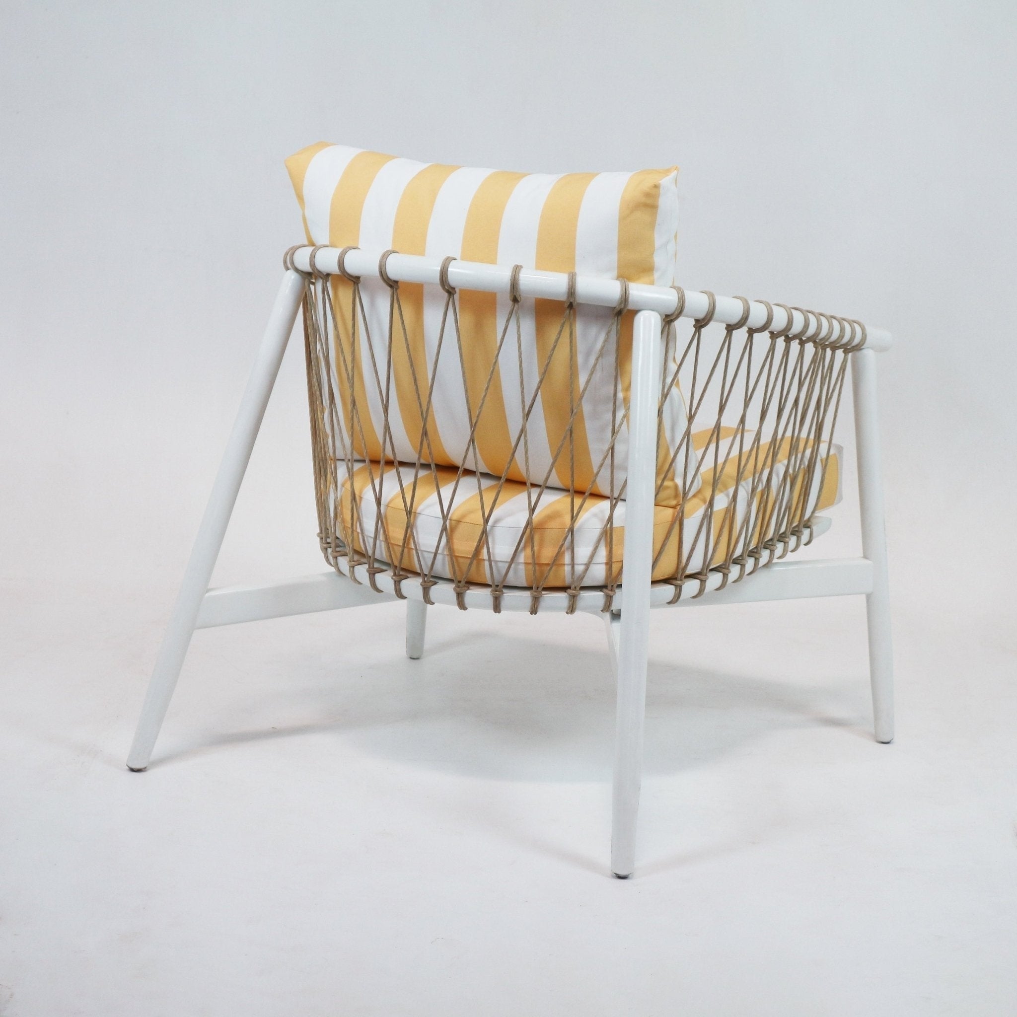 Rear three-quarter view of a modern white wood-frame lounge chair with natural rope lattice sides and yellow-and-white striped seat and back cushions.