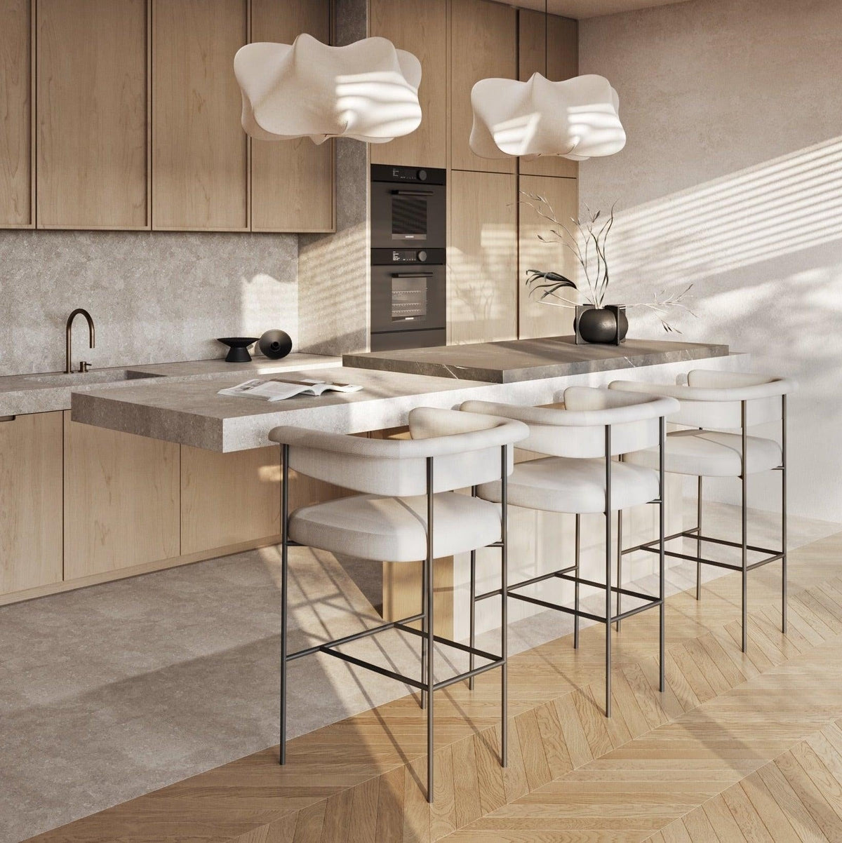 Three modern cream boucle upholstered counter stools with low rounded backs and slender black metal frames lined along a stone-topped kitchen island in a light-wood contemporary kitchen.