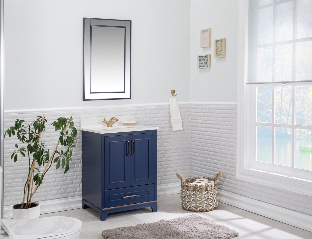 Freestanding modern solid wood single-sink vanity in navy blue with a stone countertop, brass faucet and hardware, two-door storage and drawer, styled with a mirror, towel hook, plant and woven basket in a bright bathroom.
