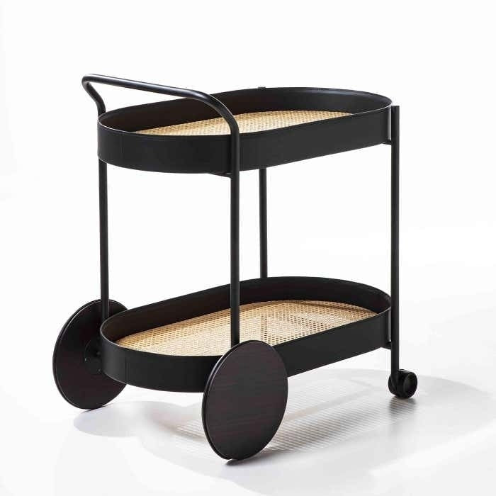 Modern two-tier bar cart with a matte black metal frame, woven rattan (cane) shelves, oversized round rear wheels and small front casters, shown on a white background.