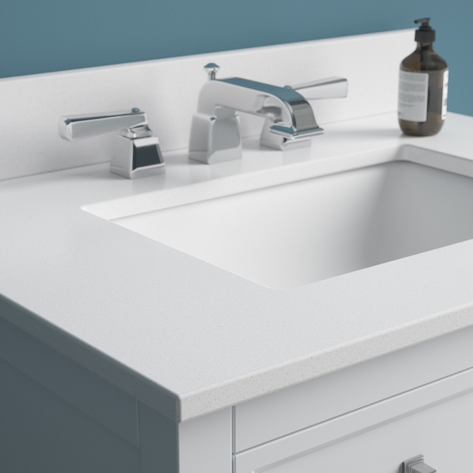 Close-up of a stone-colored vanity top on a solid wood bathroom cabinet with a white undermount ceramic sink, chrome widespread faucet with two handles, a soap dispenser, and a white drawer front.