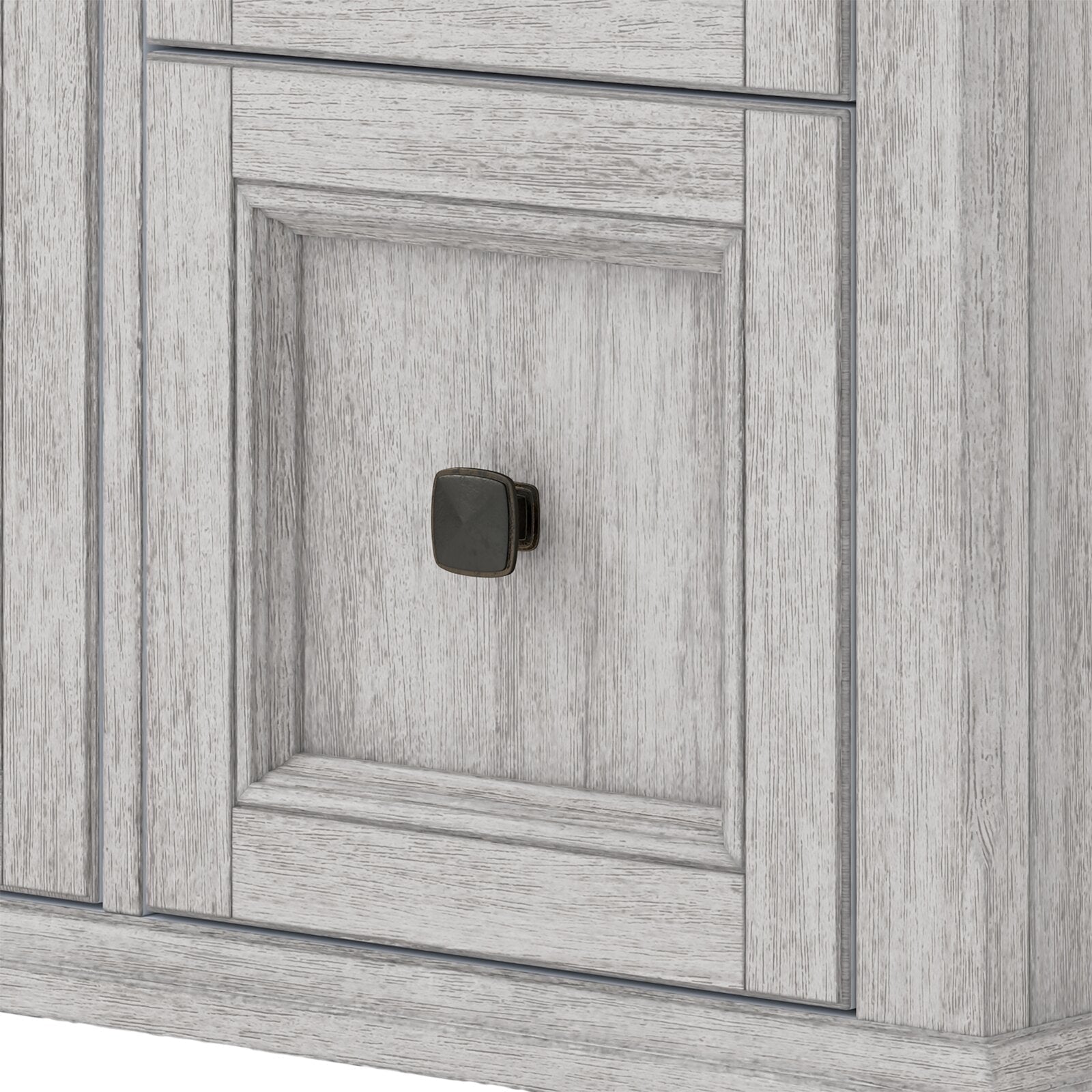 Close-up of a solid wood vanity door with a light weathered finish, recessed panel detailing and a square black metal knob in a modern contemporary style.