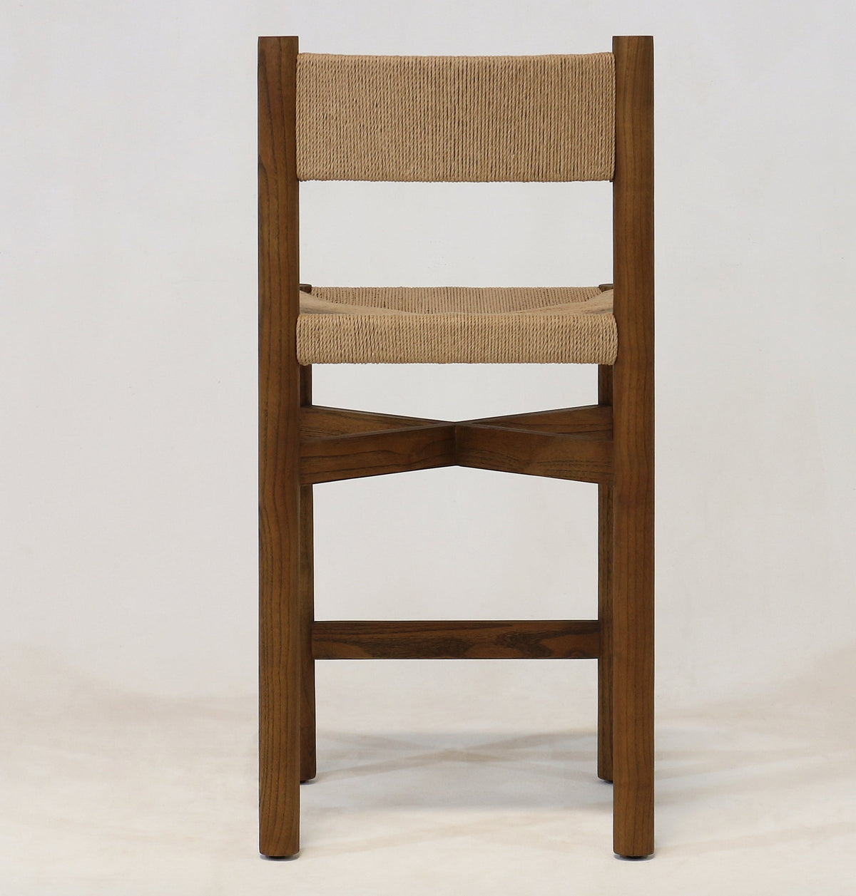 Front view of a walnut wood counter stool with a natural papercord woven seat and back, armless modern-coastal frame and X-shaped stretcher footrest shown on a plain light background.