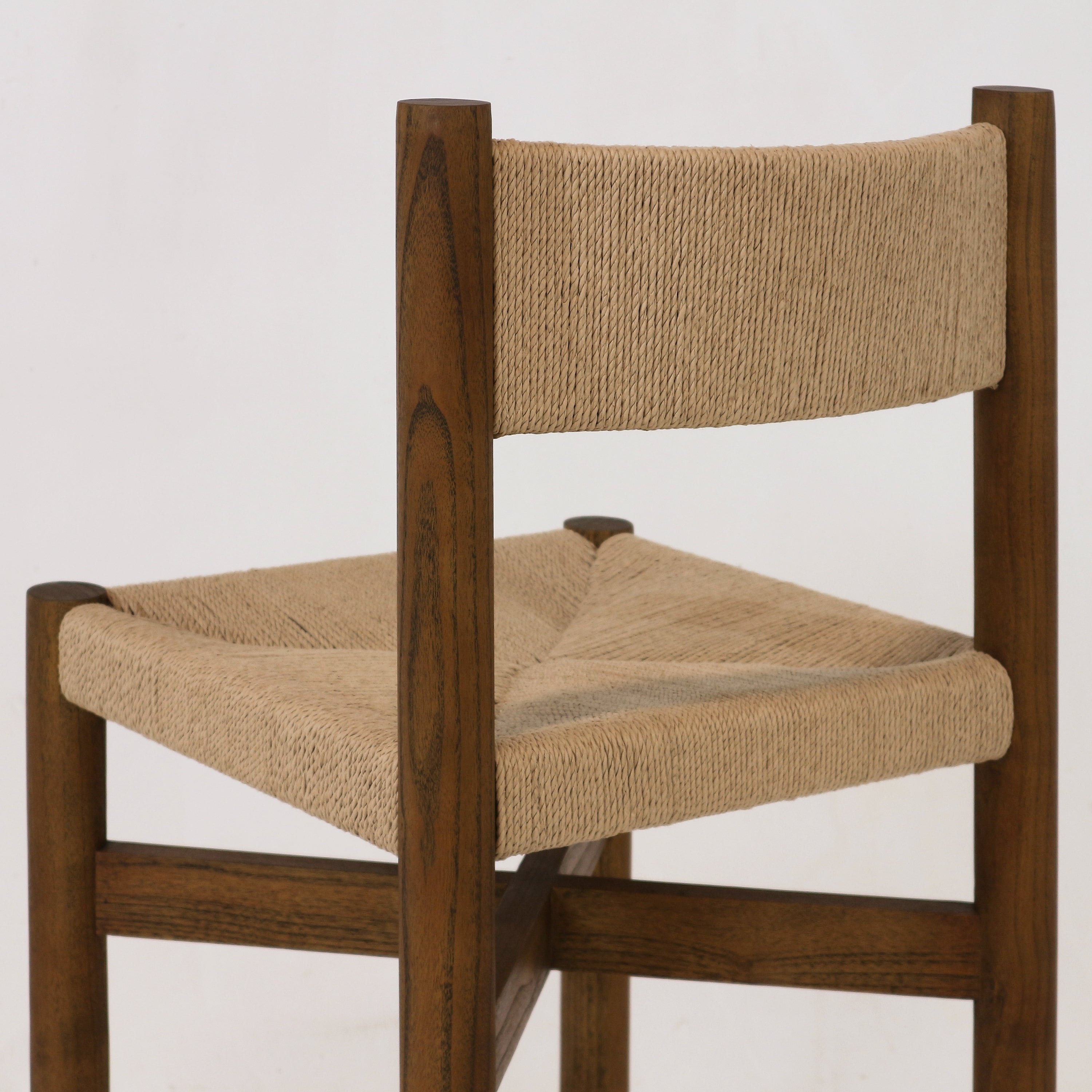Close-up of a walnut-stained solid wood stool showing a natural papercord woven seat and matching woven backrest, highlighting the textured rope weave and warm wood grain.