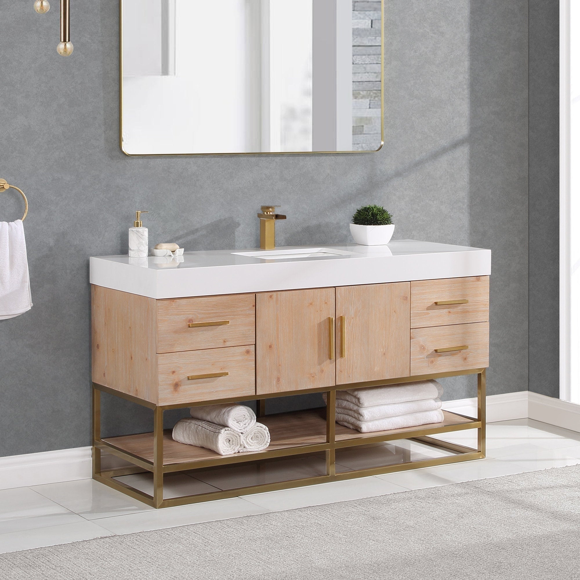 60-inch modern natural wood single-sink bathroom vanity with white composite stone top, rectangular undermount sink and single-hole brass faucet; gold metal base and hardware, open shelf with rolled white towels under a gold mirror.