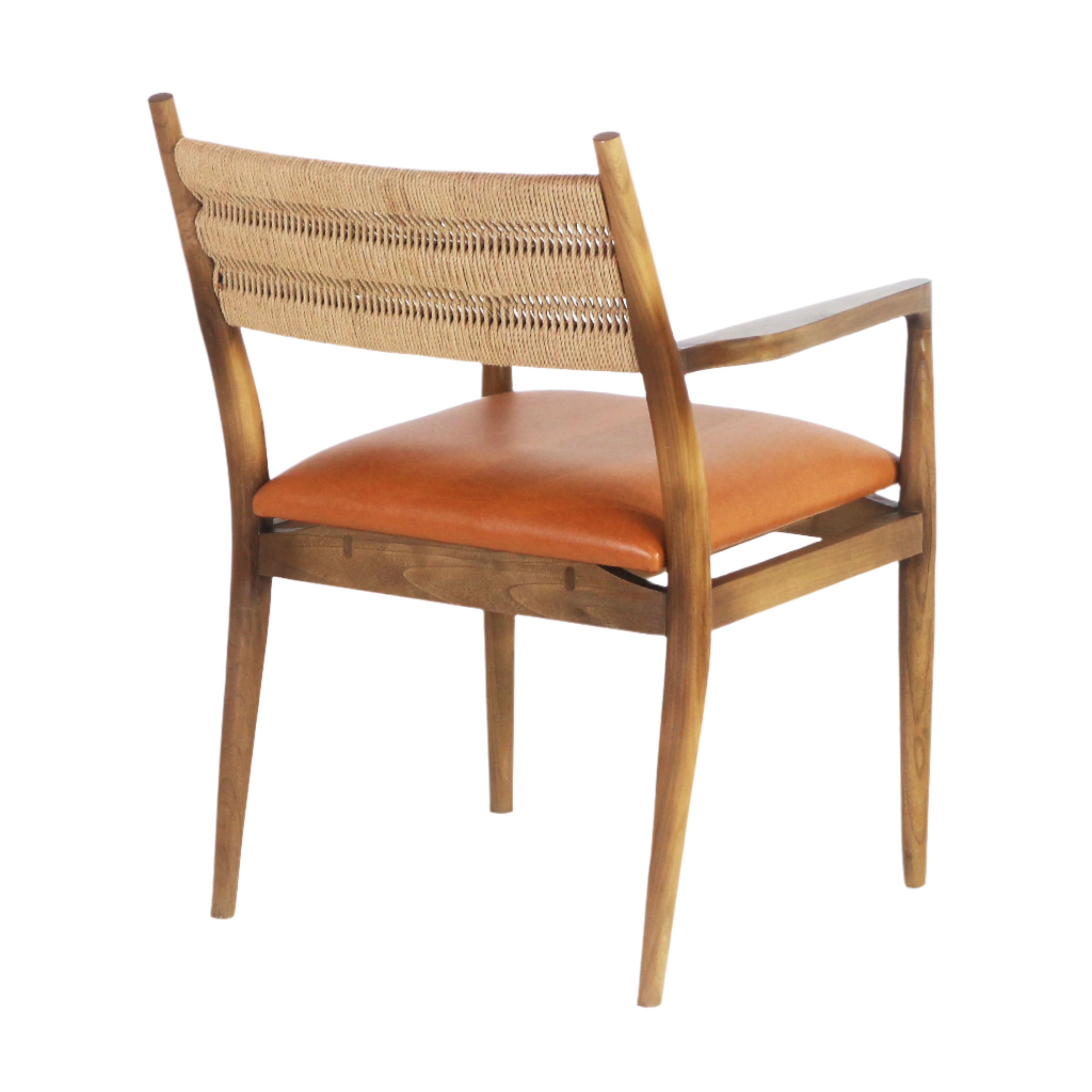 Rear three-quarter view of a coastal-style dining chair with a woven natural rope back, caramel faux-leather seat cushion and warm natural wood frame with tapered legs and armrests.