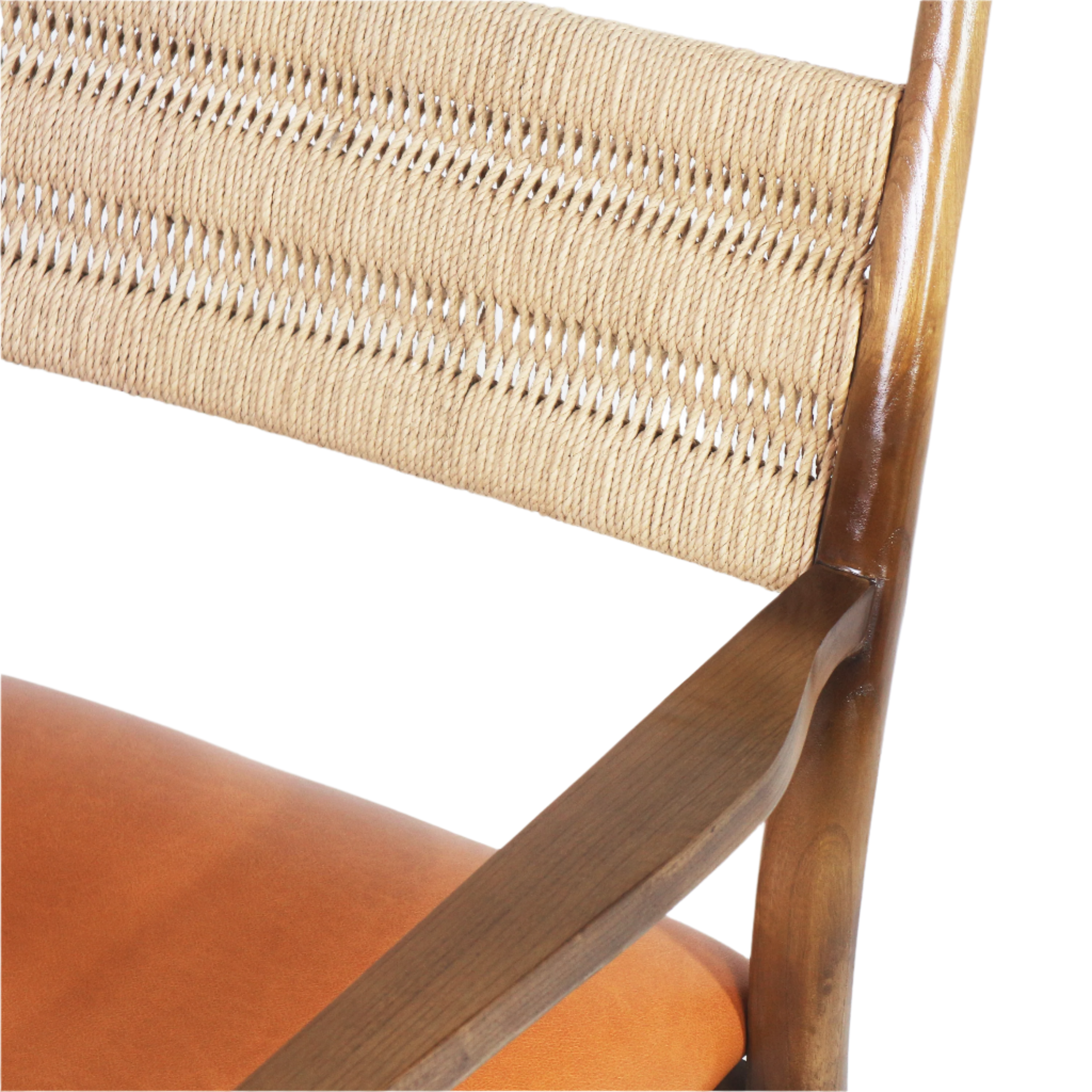 Close-up of a woven natural rope back with a curved natural wood armrest and warm brown faux-leather dining chair seat.