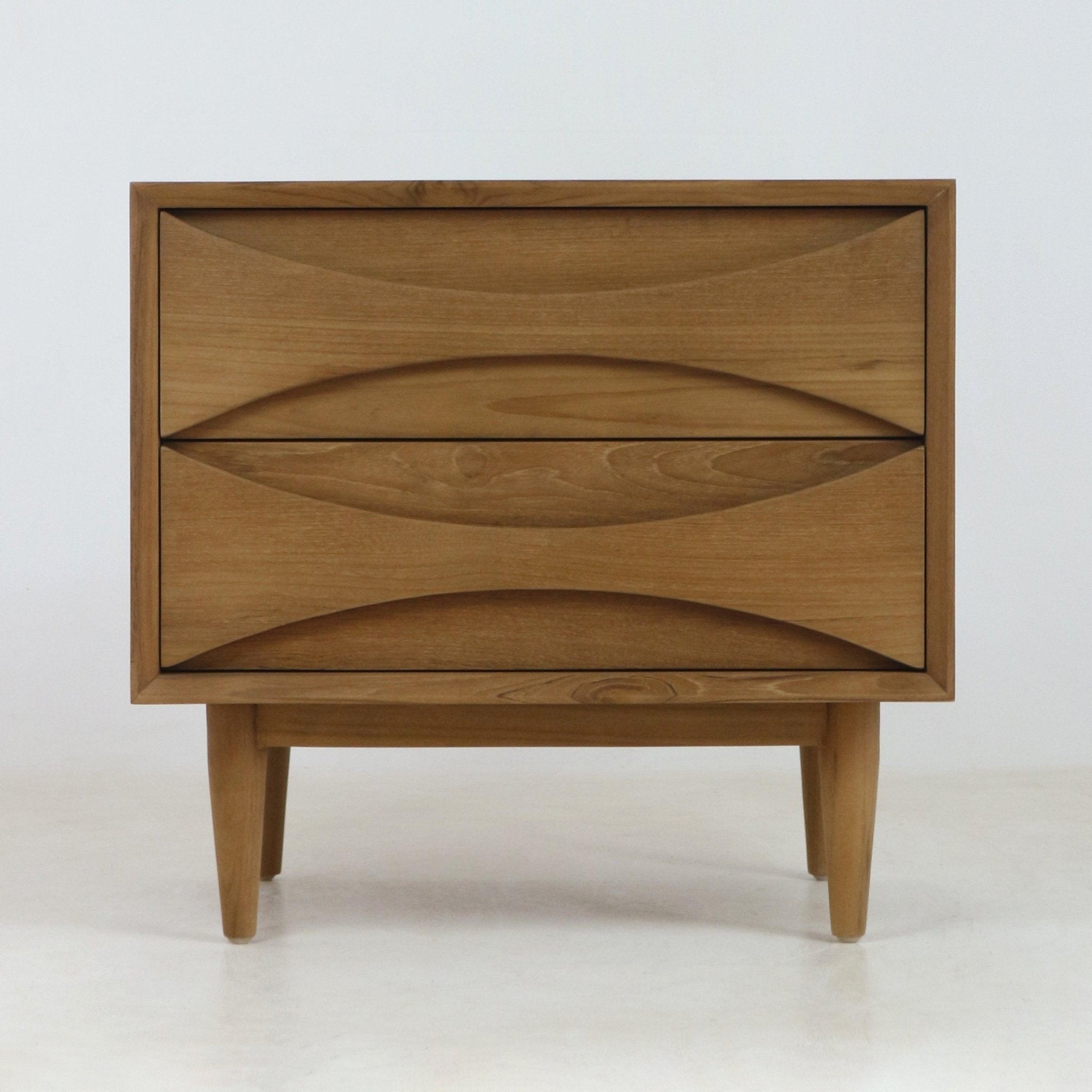 Natural teak solid wood nightstand with two drawers featuring carved recessed pulls, tapered mid-century modern legs and a clean Scandinavian silhouette.