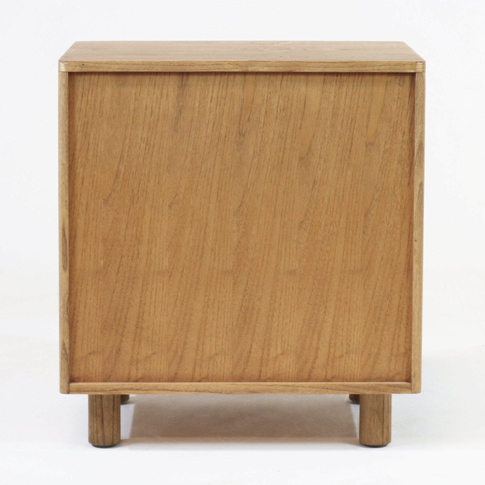 Side view of a blonde solid wood nightstand showing natural oak grain, minimalist Scandinavian-modern lines, recessed base and short cylindrical legs against a white studio background.