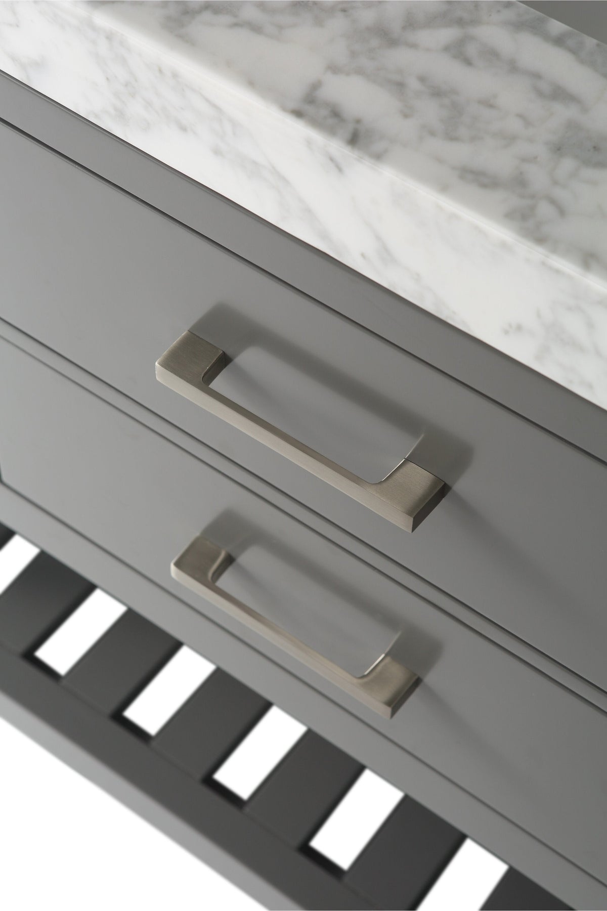Close-up of a stone-top solid wood bathroom vanity showing stone-gray drawer fronts with brushed-gold rectangular handles, the marble-patterned stone countertop edge and a slatted lower shelf in a modern style.