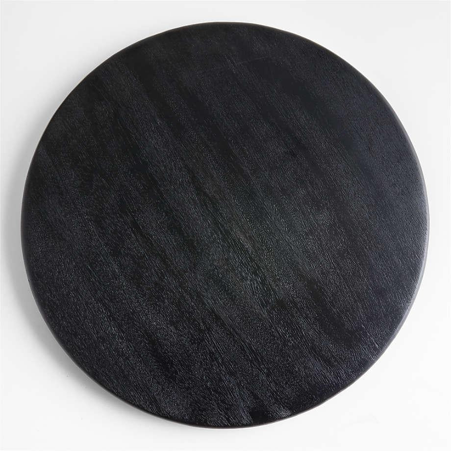 Top-down view of a round black teak butter board made from solid wood with visible grain on a white background