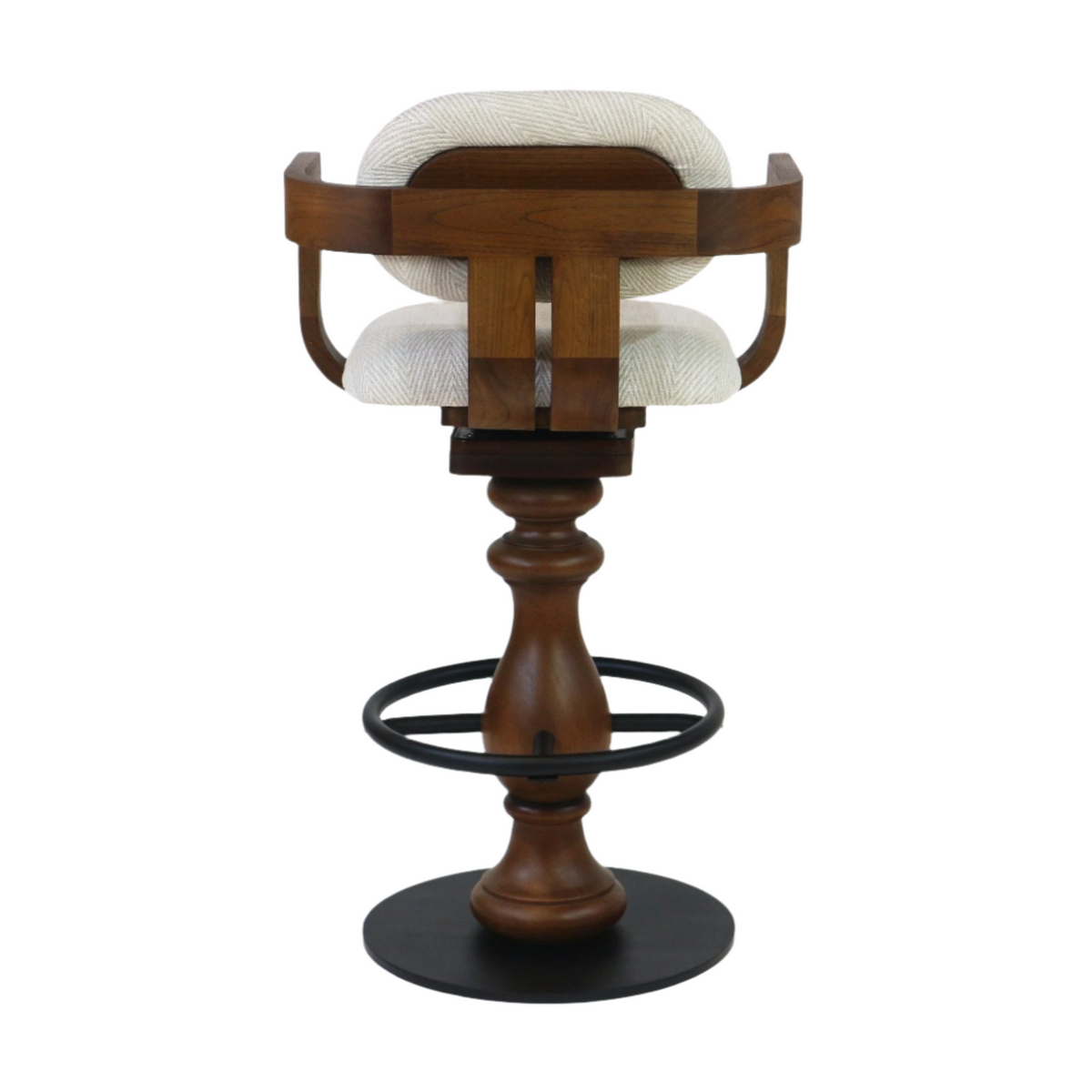 Rear view of a swivel bar stool with light beige fabric upholstery, curved teak wood back and seat frame, turned teak pedestal, black metal ring footrest and round black metal base.