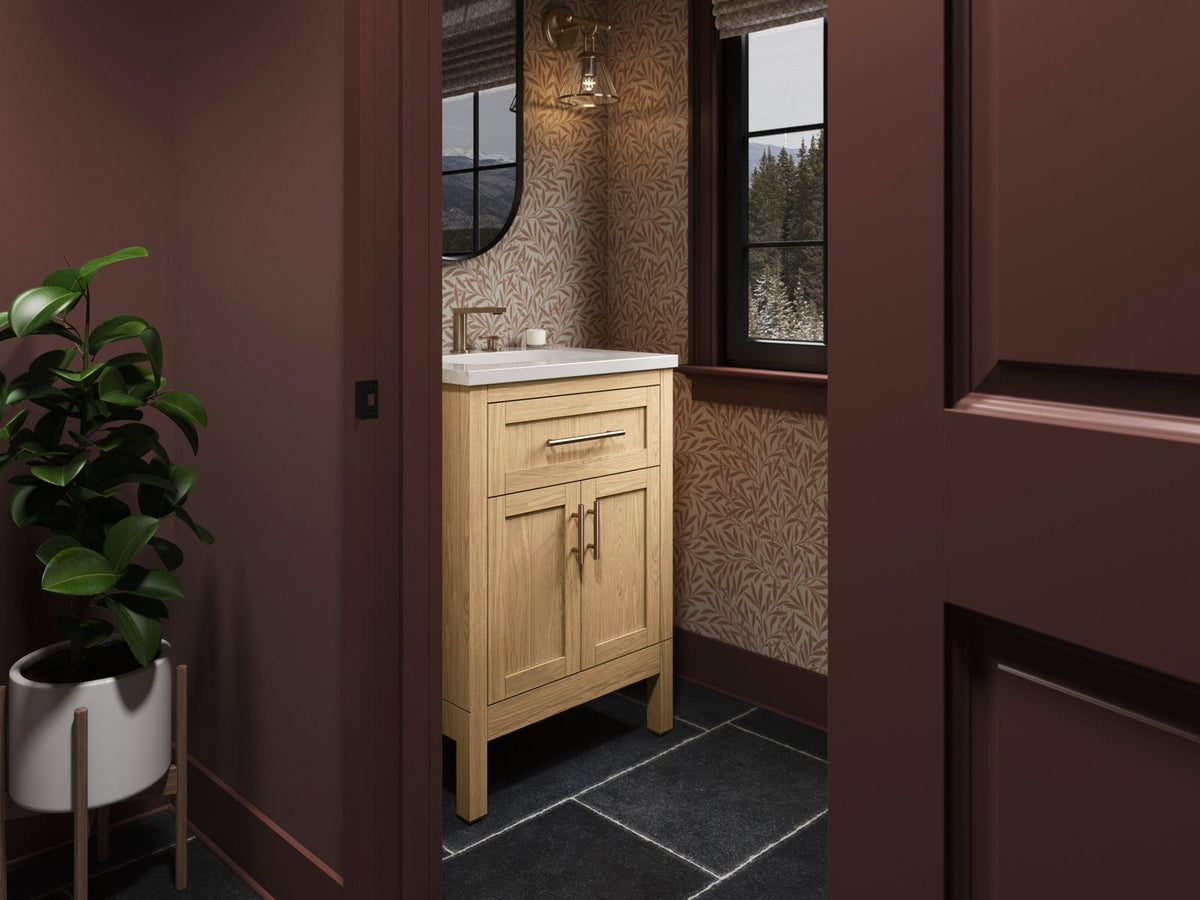 24-inch natural solid wood bathroom vanity with a stone top and white ceramic sink, single modern faucet, soft-close drawer and double-door storage, freestanding in a contemporary bath with patterned wallpaper and dark tile floor.