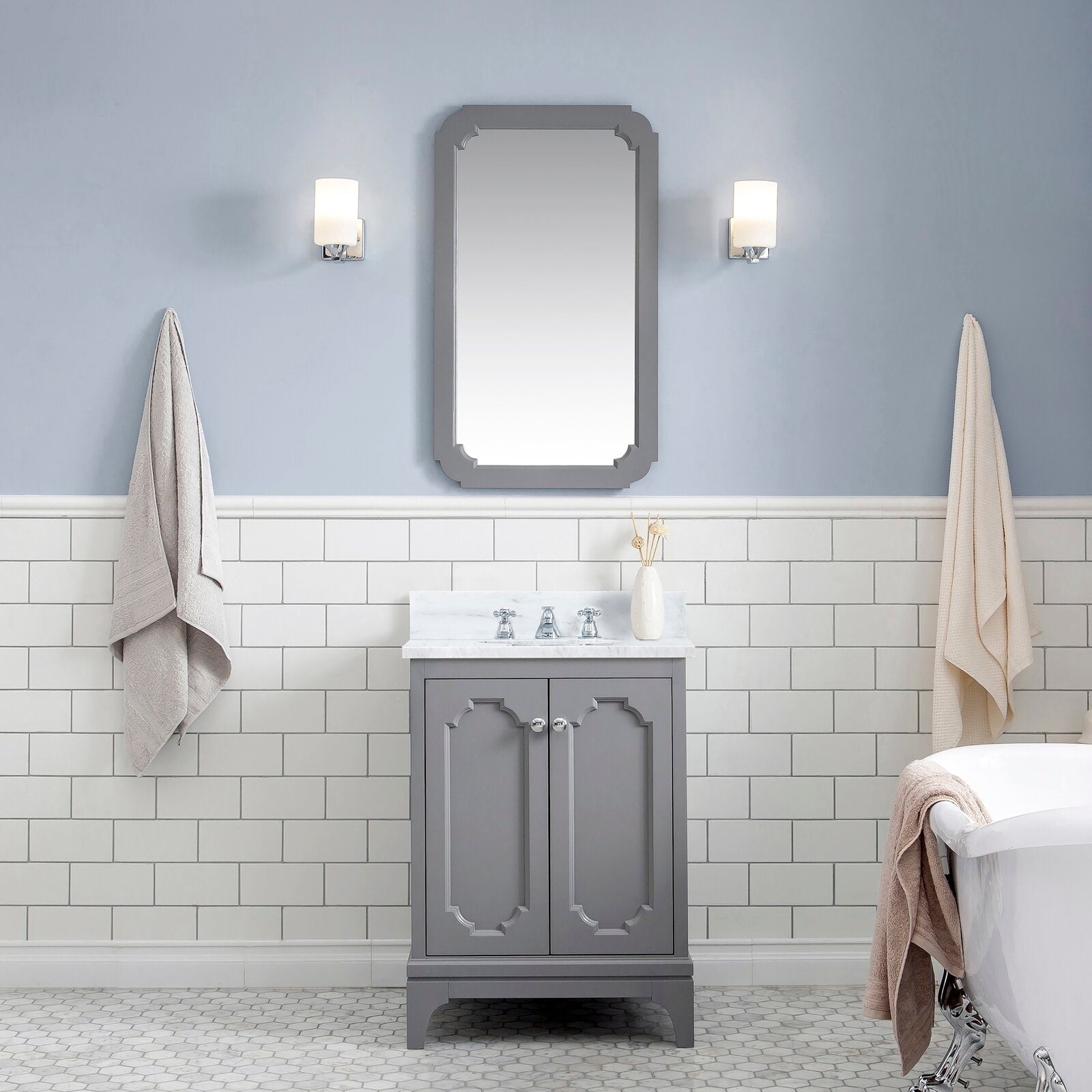 Single-sink cashmere grey vanity with Carrara white marble countertop, chrome classic faucet and matching framed mirror, flanked by two wall sconces over white subway tile and hex floor tile next to a clawfoot tub.